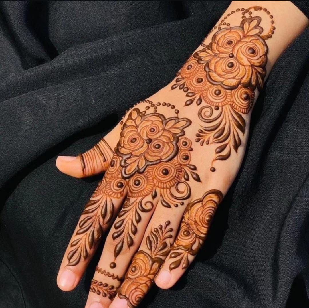 A person showing henna on their hands with a dark background