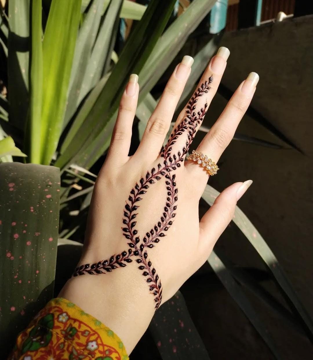 A person showing henna on their hands with a green background